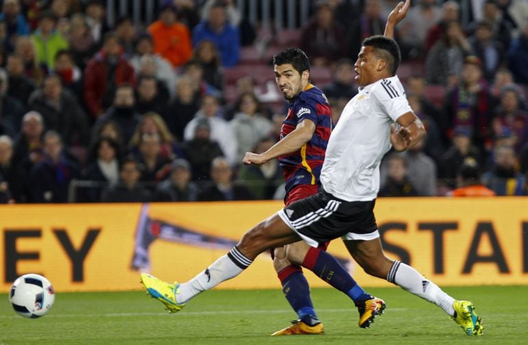 El delantero uruguayo del FC Barcelona Luís Suárez dispara a puerta para marcar el primer gol ante el defensa brasileño del Valencia Santos 