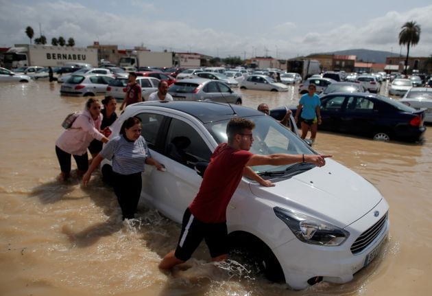 Varios vecinos de la localidad de Orihuela intentan proteger un coche de las riadas.