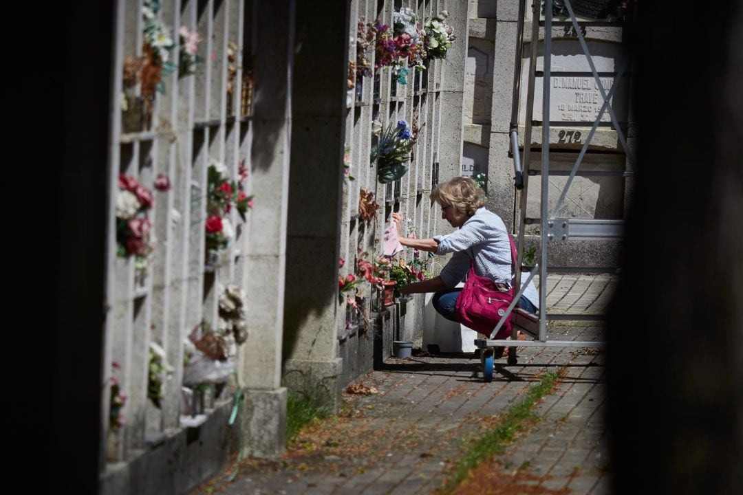 Una mujer deposita flores en un cementerio.