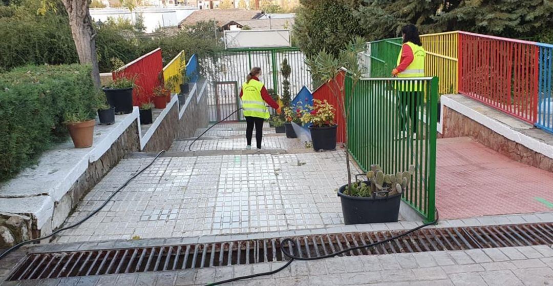 Trabajadoras del Ayuntamiento de Ibros desinfectan la entrada al colegio de la localidad.