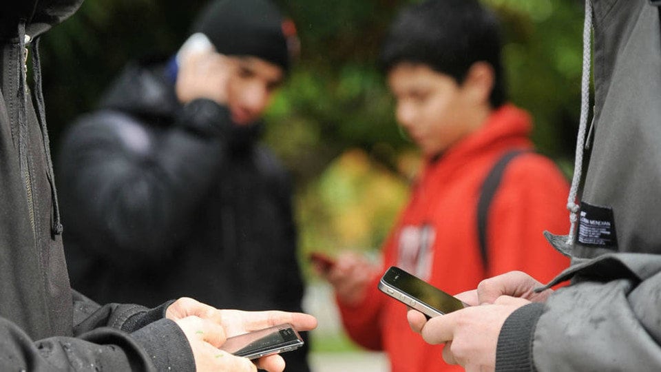 Menores con sus teléfonos móviles.