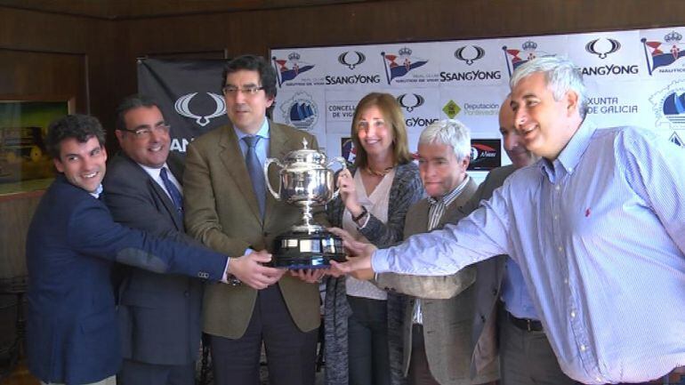 Las personas que acudieron a la rueda de prensa de la presentación del campeonato sujetando la copa de España que será entregada a la flota ganadora de la regata.