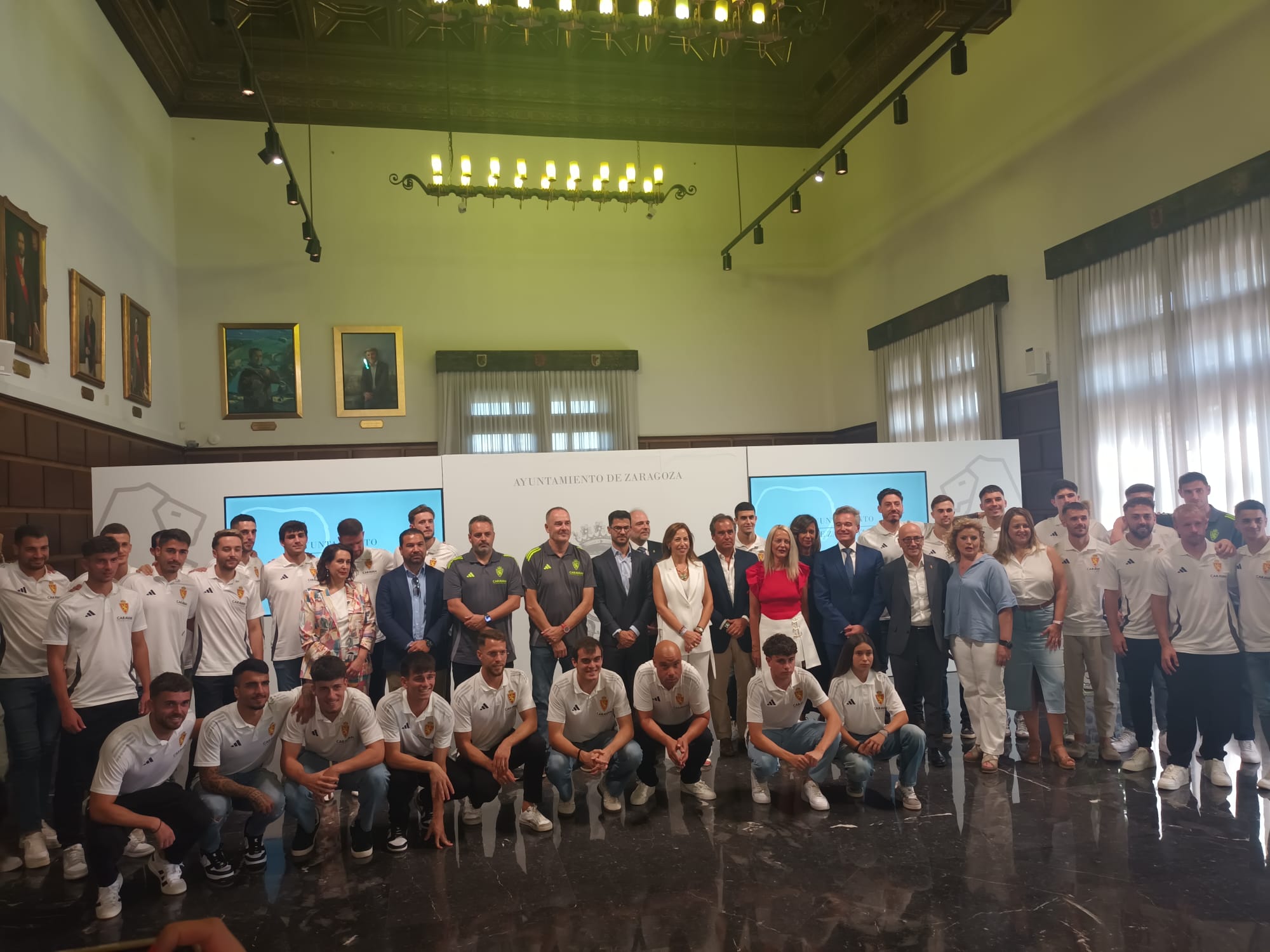 Natalia Chueca, alcaldesa de Zaragoza, junto a la plantilla del primer equipo del Real Zaragoza, su cuerpo técnico y miembros de la directiva, entre ellos el director general, Fernando López