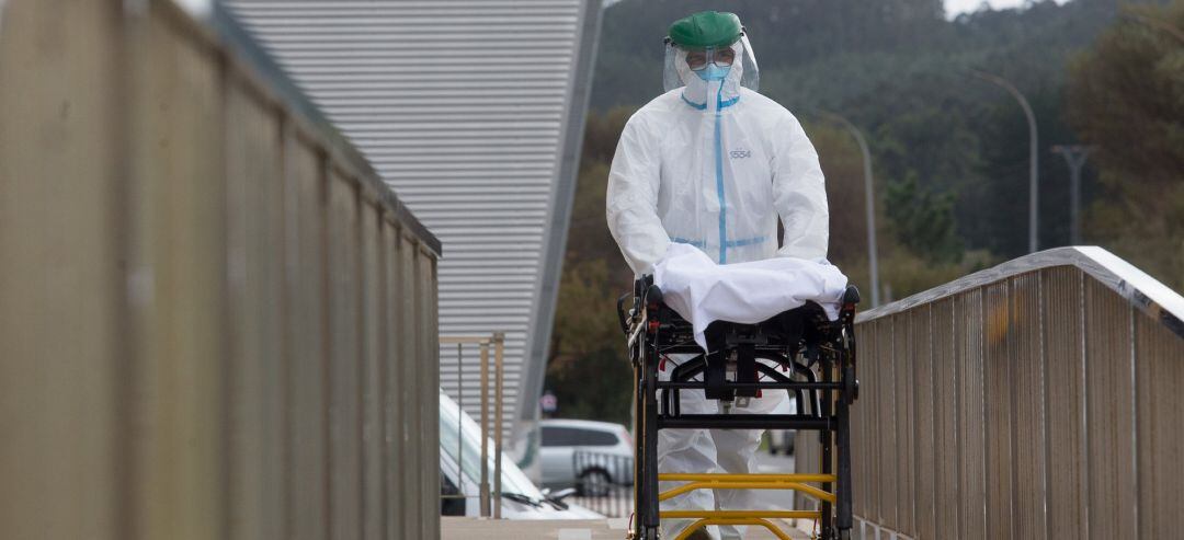 Un trabajador sanitario totalmente protegido traslada una camilla en las inmediaciones de una residencia de ancianos.