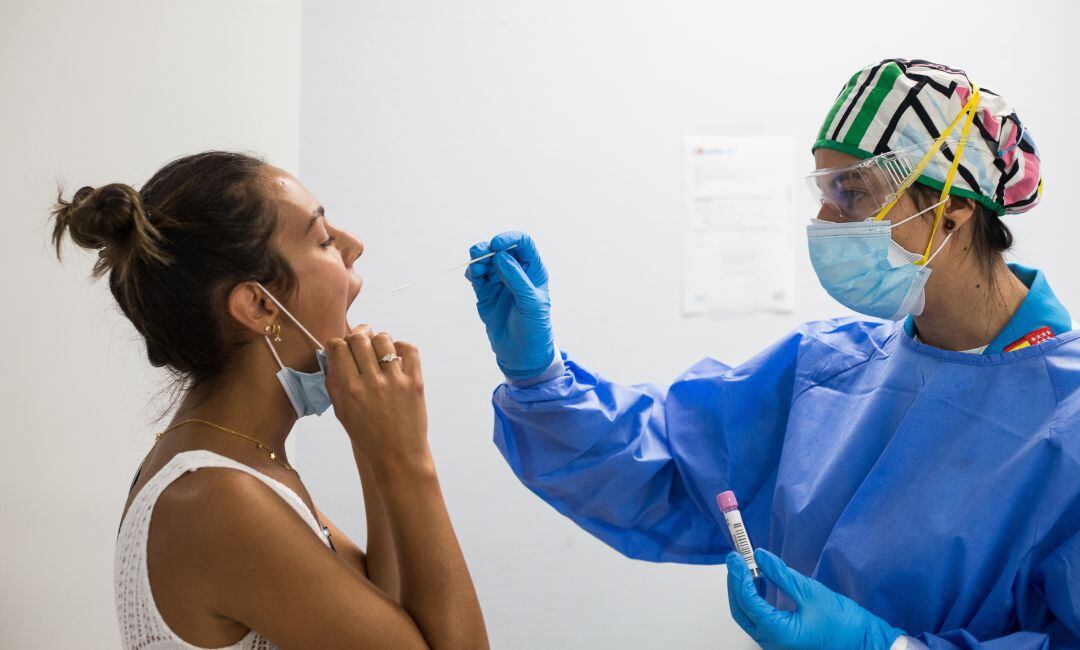 Una sanitaria practica una prueba PCR a una joven.