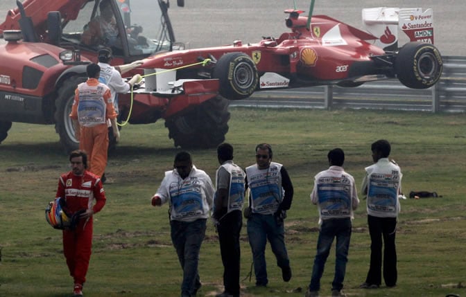 Fernando Alonso se marcha mientras su coche es recogido por la grúa