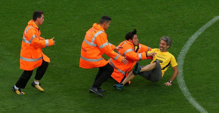 Los miembros de seguridad neutralizan al hincha que saltó al terreno de juego