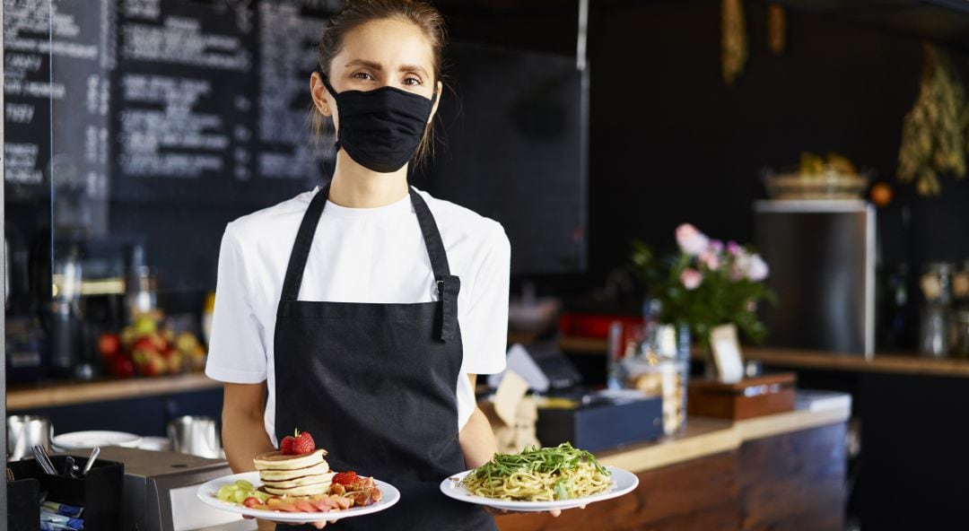 Una camarera está a punto de servir un par de platos en un restaurante