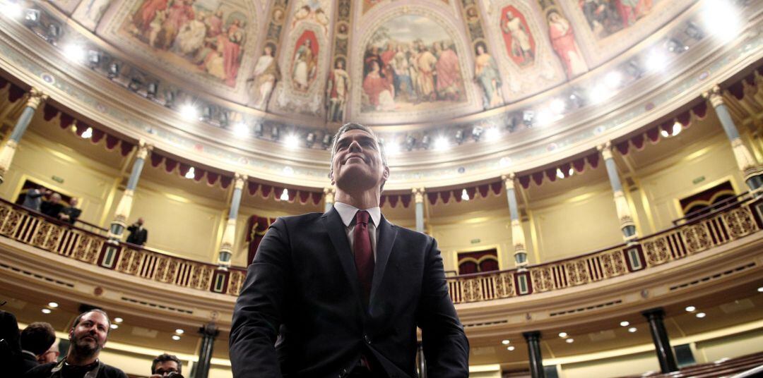 El presidente del Gobierno, Pedro Sánchez, posa sonriente en el hemiciclo del Congreso de los Diputados, tras obtener una votación favorable a su investidura