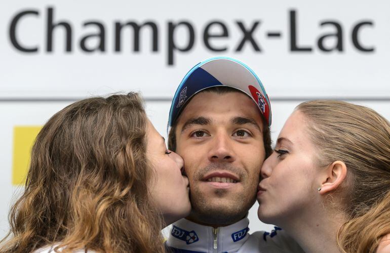 Beso de dos azafatas a un ciclista tras ganar una etapa.
