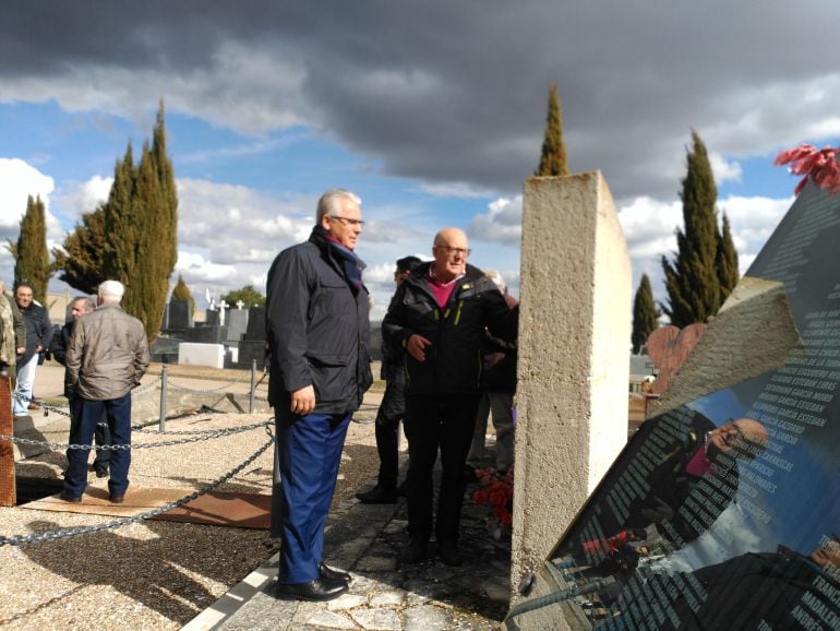 Baltasar Garzón observa el monumento de recuerdo a las víctimas del franquismo del cementerio de Aranda atendiendo a las explicaciones de José María Rojas, representante de asociaciones memorialistas