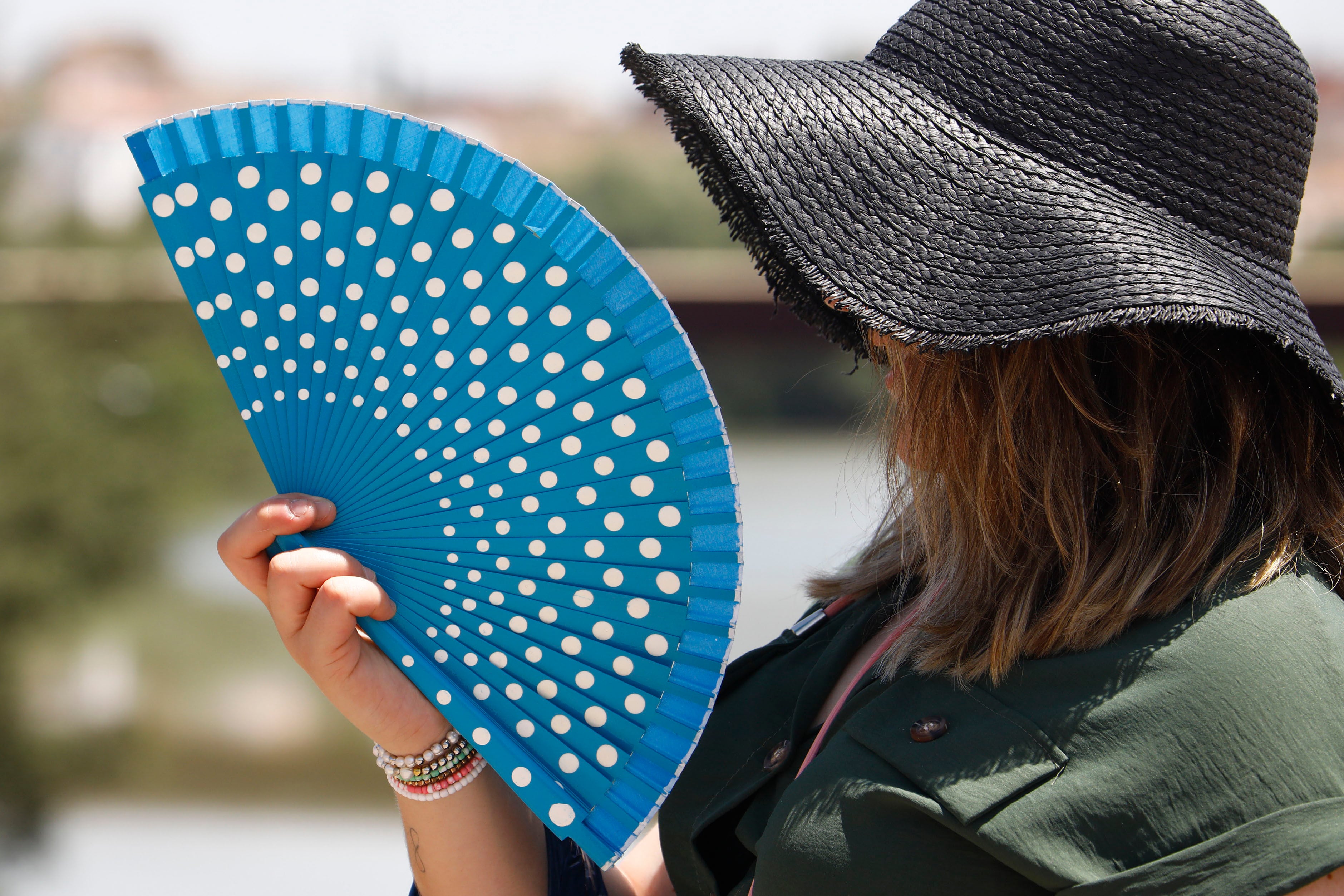 Una mujer se protege de las altas temperaturas con un sombrero y un abanico. EFE/Salas