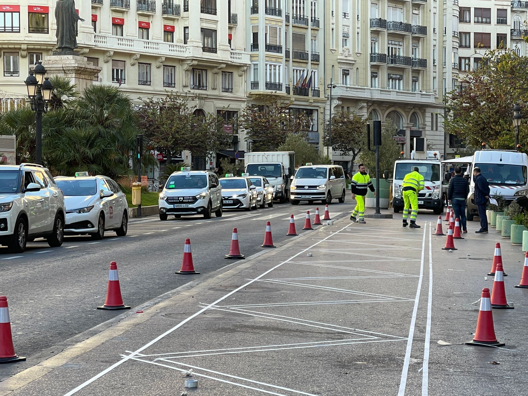 Operarios trabajan en el cambio de acera de la parada de taxis en la plaza del Ayuntamiento de València para habilitar la nueva parada de la EMT