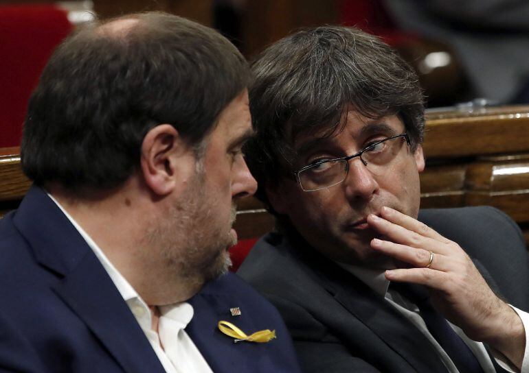 El presidente de la Generalitat, Carles Puigdemont, conversa con el vicepresidente, Oriol Junqueras (i), durante el pleno monográfico celebrado esta tarde para abordar la respuesta a la aplicación del artículo 155 de la Constitución. 