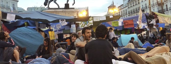 Un joven bosteza hoy al amanecer en la Puerta del Sol de Madrid, después de otra noche de acampada de miles de personas para reclamar cambios en el modelo democrático español,