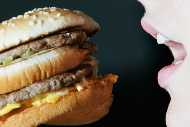 Una mujer se prepara para dar un mordisco a una hamburguesa, en una imagen de recurso