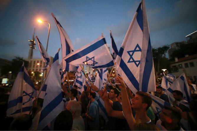 Los israelíes sostienen banderas durante una protesta en Tel Aviv