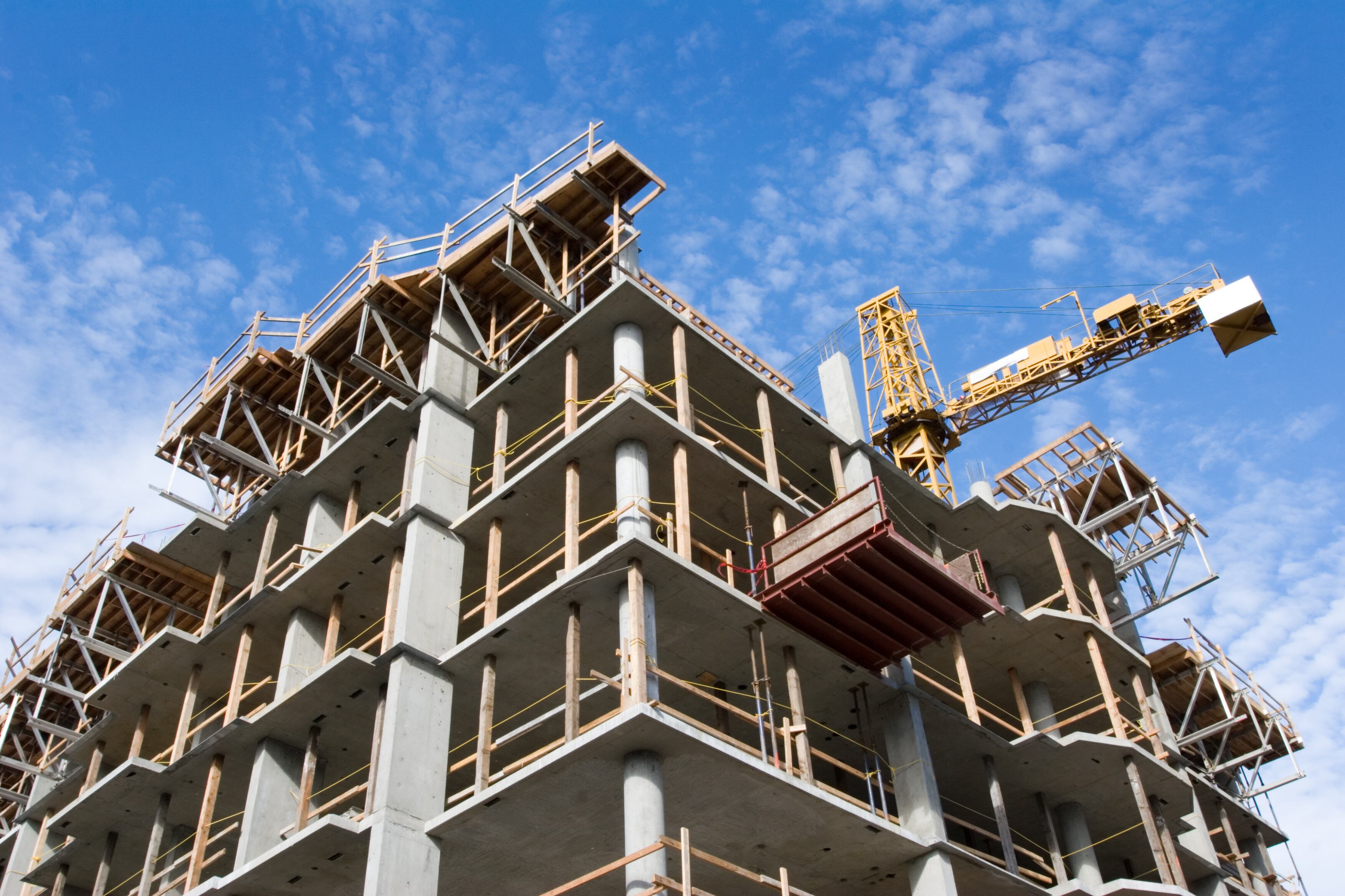 Reinforced steel & concrete building under construction.  Safety guard rails, flyforms and tower crane