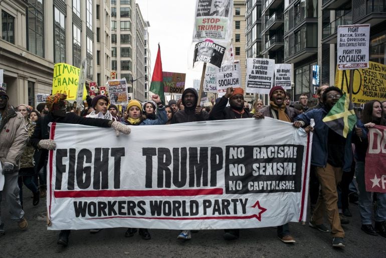 Cientas de personas manifiestan con pancartas durante una protesta cerca de una de las rutas del desfile de investidura de Donald J. Trump como 45º presidente de los Estados Unidos en Washington