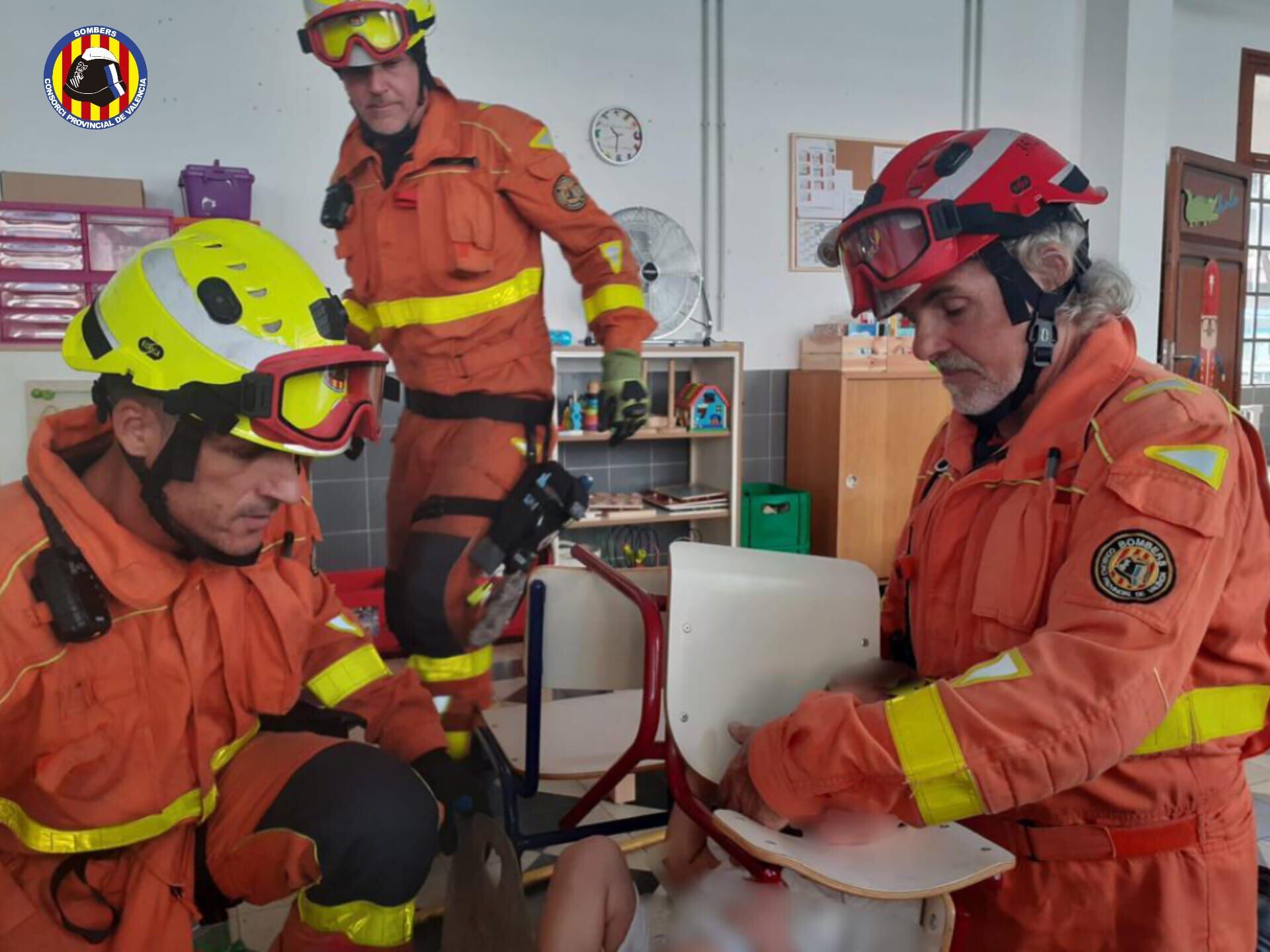 Los bomberos intentan desencajar la cabeza del pequeño de la silla.