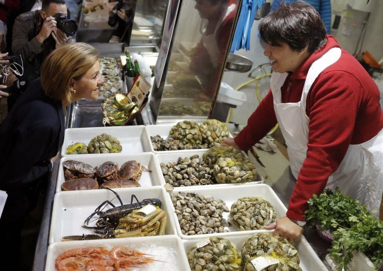 La secretaria general del PP, María Dolores de Cospedal, habla con una pescadera durante la visita que ha realizado al mercado de abastos en Santiago de Compostela