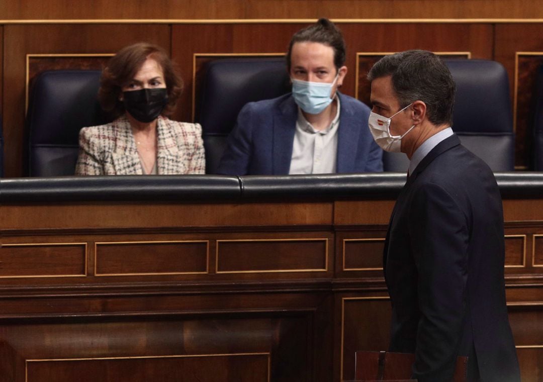 El presidente del Gobierno, Pedro Sánchez, pasa por delante la vicepresidenta primera del Gobierno, Carmen Calvo, y el vicepresidente segundo del Gobierno, Pablo Iglesias, durante una sesión de control