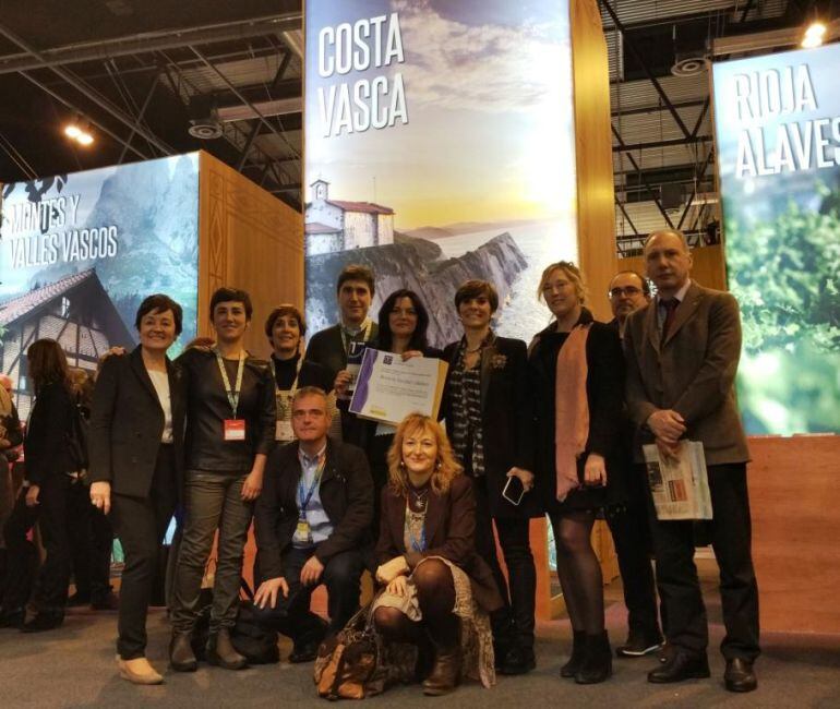 Beatriz Escobar, acompañada del resto de la expedición de Debabarrena en FITUR, muestra en el centro de la imagen la acreditación del premio recibido