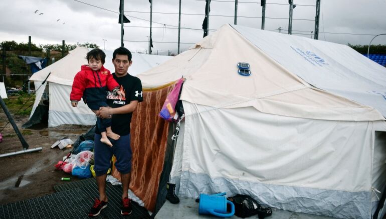 Un refugiado afgano sostiene a su hijo en el exterior de su tienda de campaña en el campo de refugiados de Hellinikon, en un suburbio del sur de Atenas.