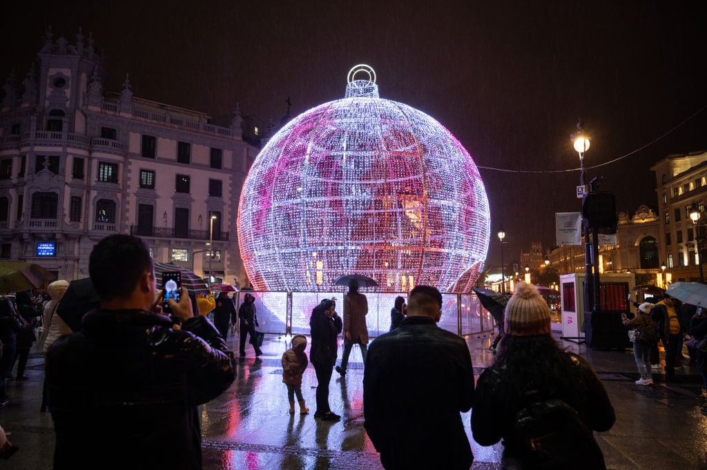 Varios turistas contemplan las luces de Navidad en Madrid.