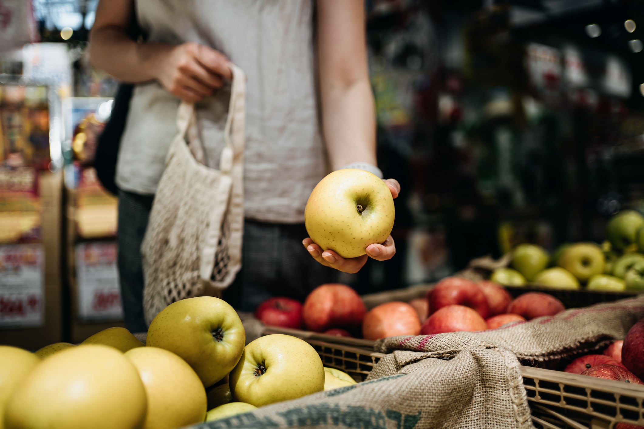 Una mujer coge una manzana en un mercado