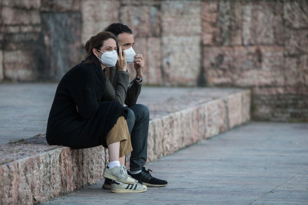 Una pareja con mascarillas descansa en la Plaza de Colón de Madrid durante la fase 0 de la desescalada donde las salidas para realizar deporte o pasear.