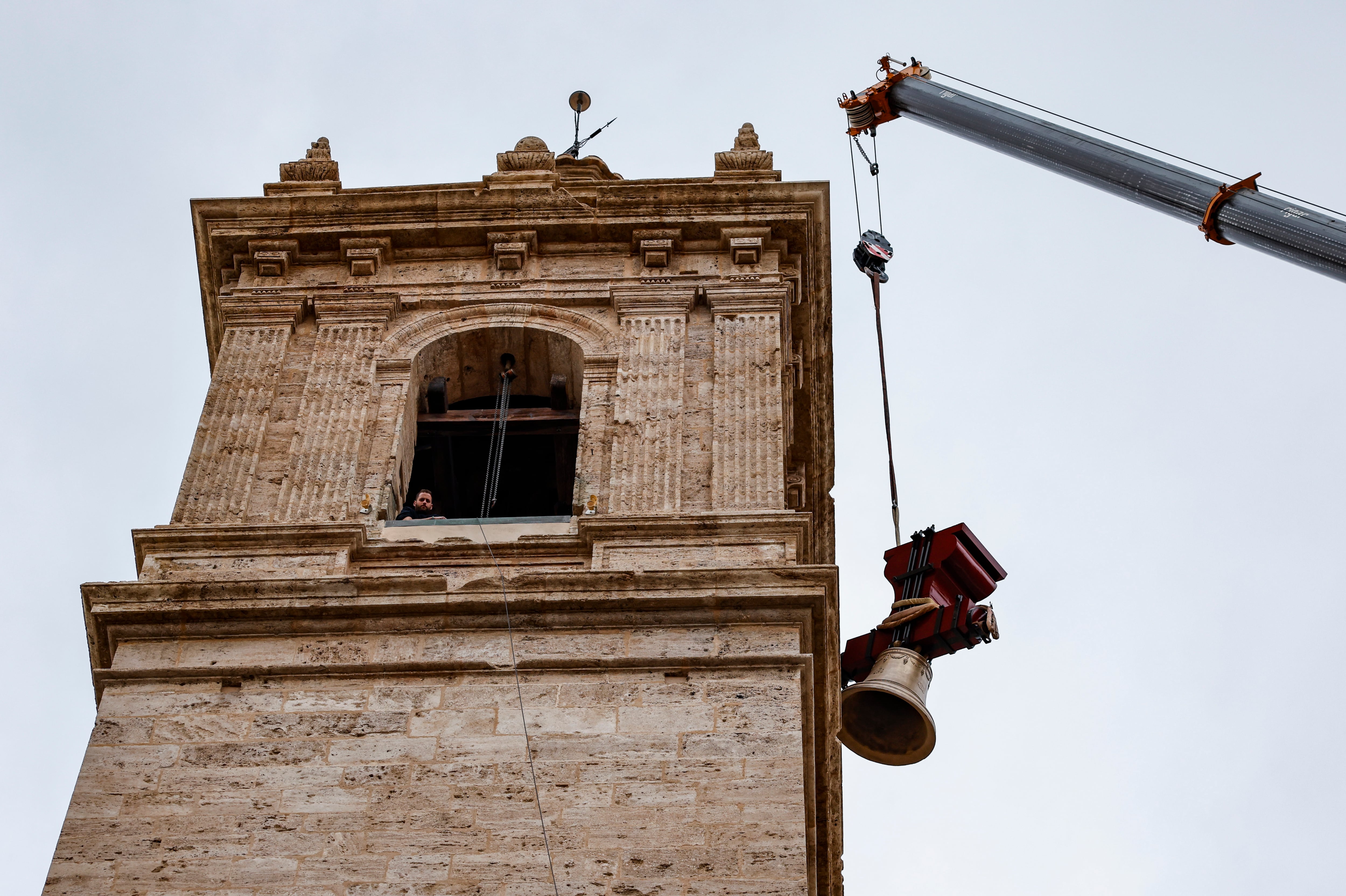 GRAFCVA8464. VALENCIA, 21/02/2024.- &quot;El Borrego&quot;, la campana de uso litúrgico más grande de Valencia, volverá al campanario de la iglesia de los Santos Juanes de Valencia tras pasar dos años entre el proceso de restauración y haber estado expuesta en la parroquia para ser vista de cerca por los feligreses. En la imagen un operario observa, desde la torre de la iglesia, el izado de una de las campanas. EFE/Ana Escobar
