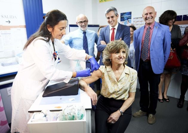 Una trabajadora del Centro de Salud del barrio de Cazoña vacuna a la ministra de Sanidad, Consumo y Bienestar Social en funciones, María Luisa Carcedo de la gripe, tras el acto de presentación de la campaña de vacunación contra la gripe, en Santander.