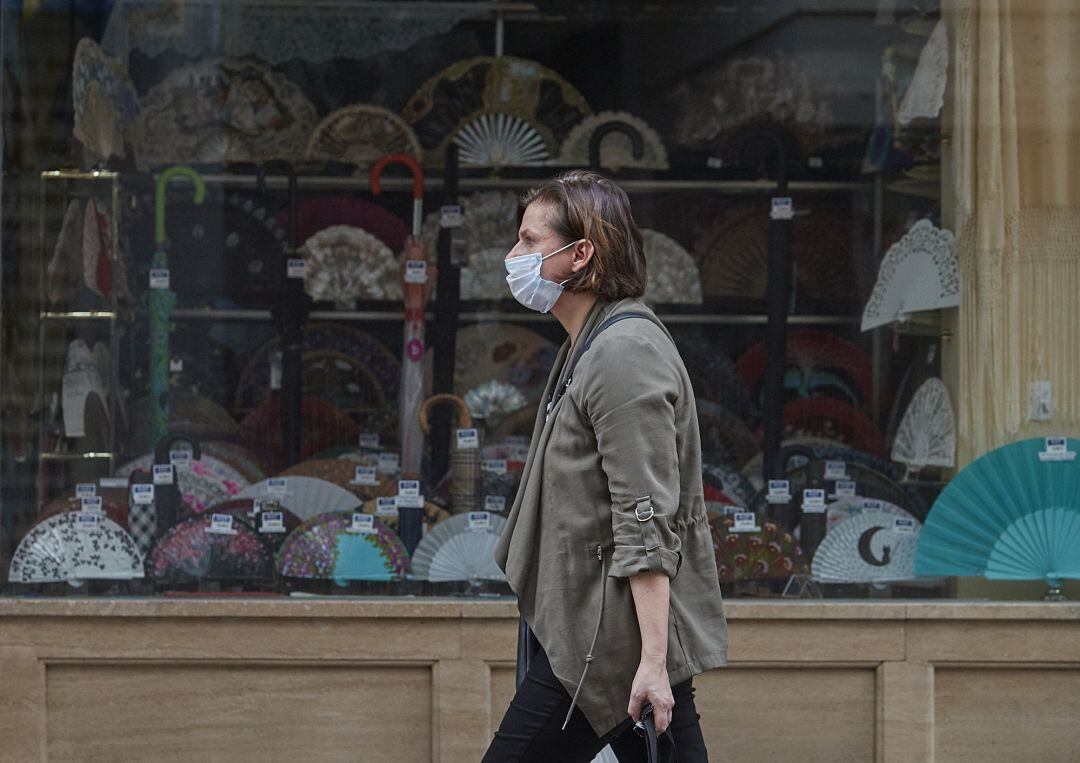 Una mujer andando por el centro de Sevilla con una mascarilla durante el Miércoles Santo 