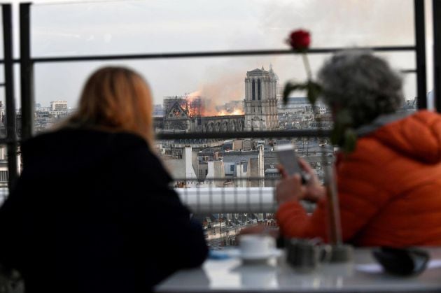 Personas observan un incendio en la catedral de Notre Dame este lunes en París, Francia