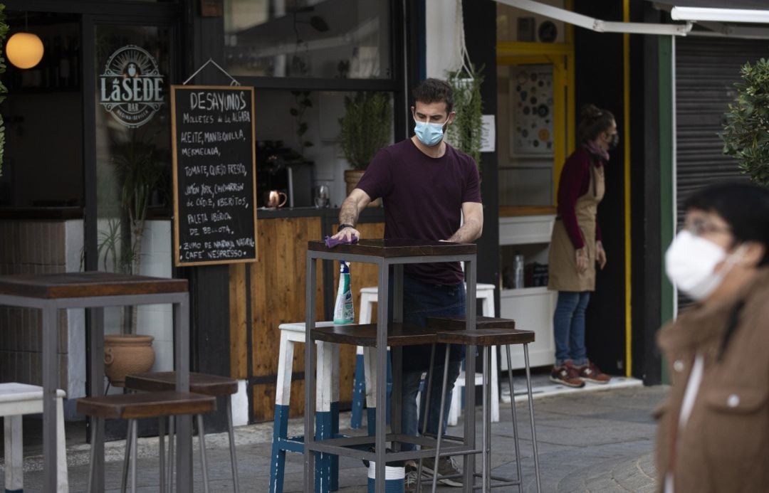 Un camarero limpia la mesa de la terraza de un bar.