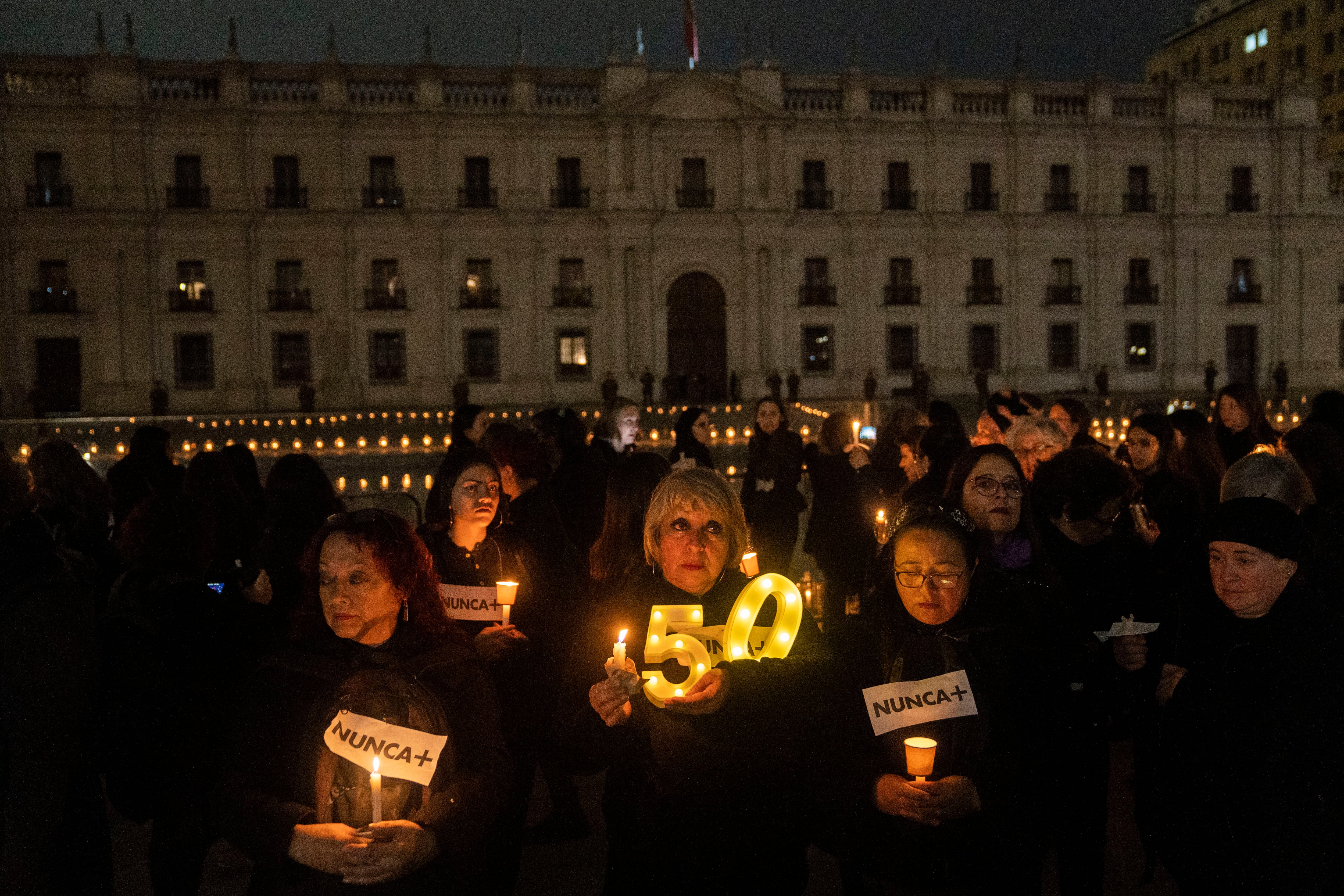 Mujeres participan de la velada en conmemoración de los 50 años del golpe de estado contra el gobierno democrático de Salvador Allende, en Santiago (Chile).