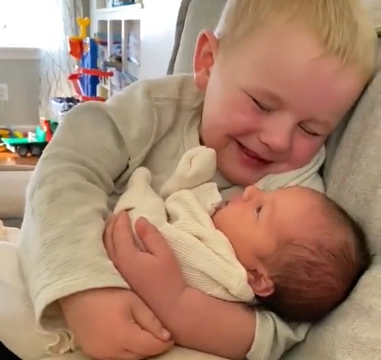 El niño sonríe tras ver por primera vez a su hermana.