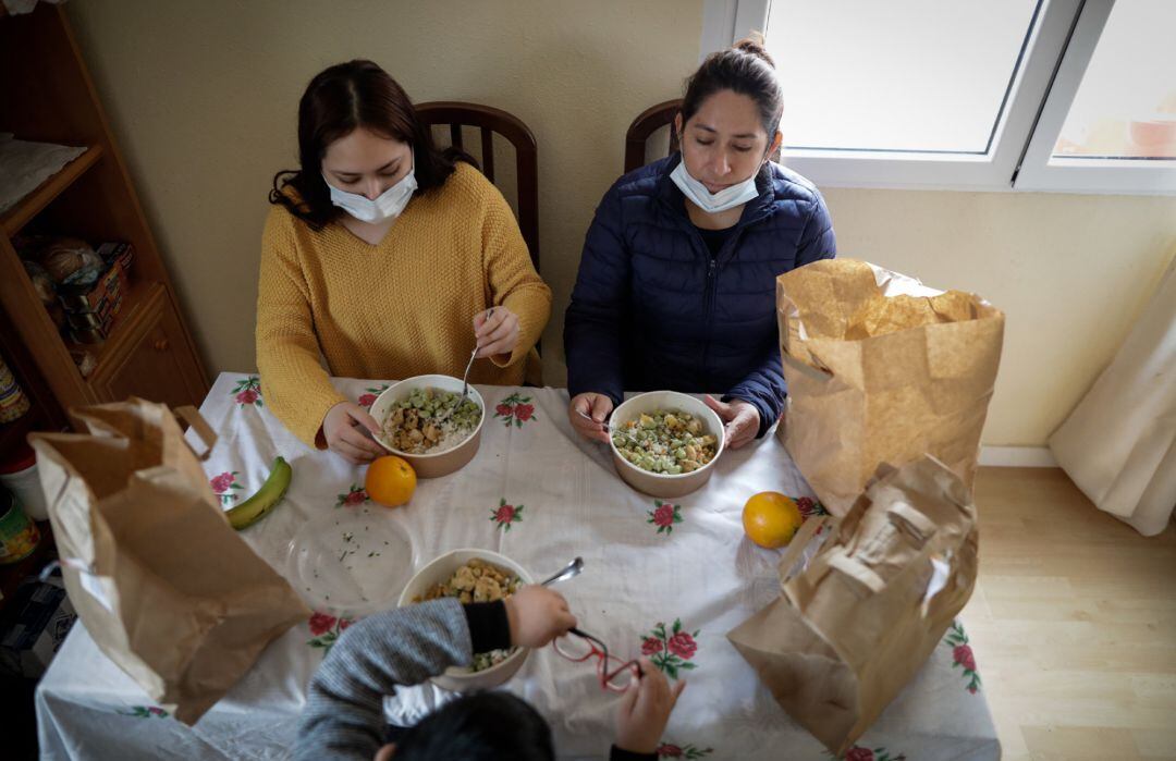 Dos mujeres y un niño en su casa en Carabanchel con el menú de la ONG del chef José Andrés, que reparte a las familias más necesitadas