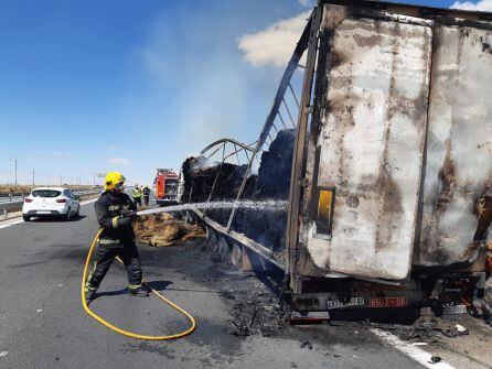 Un agente de bomberos refresca los restos del remolque afectado