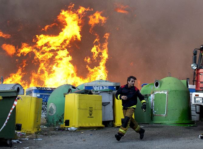 Un bombero escapa de las llamas que salen del punto limpio, donde se ha iniciado un incendio que ha quemado unas 20 hectareas en los alrededores de Ourense. En esta ciudad se ha llegado a declarar el nivel 1 de emergencia por la proximidad del fuego a las