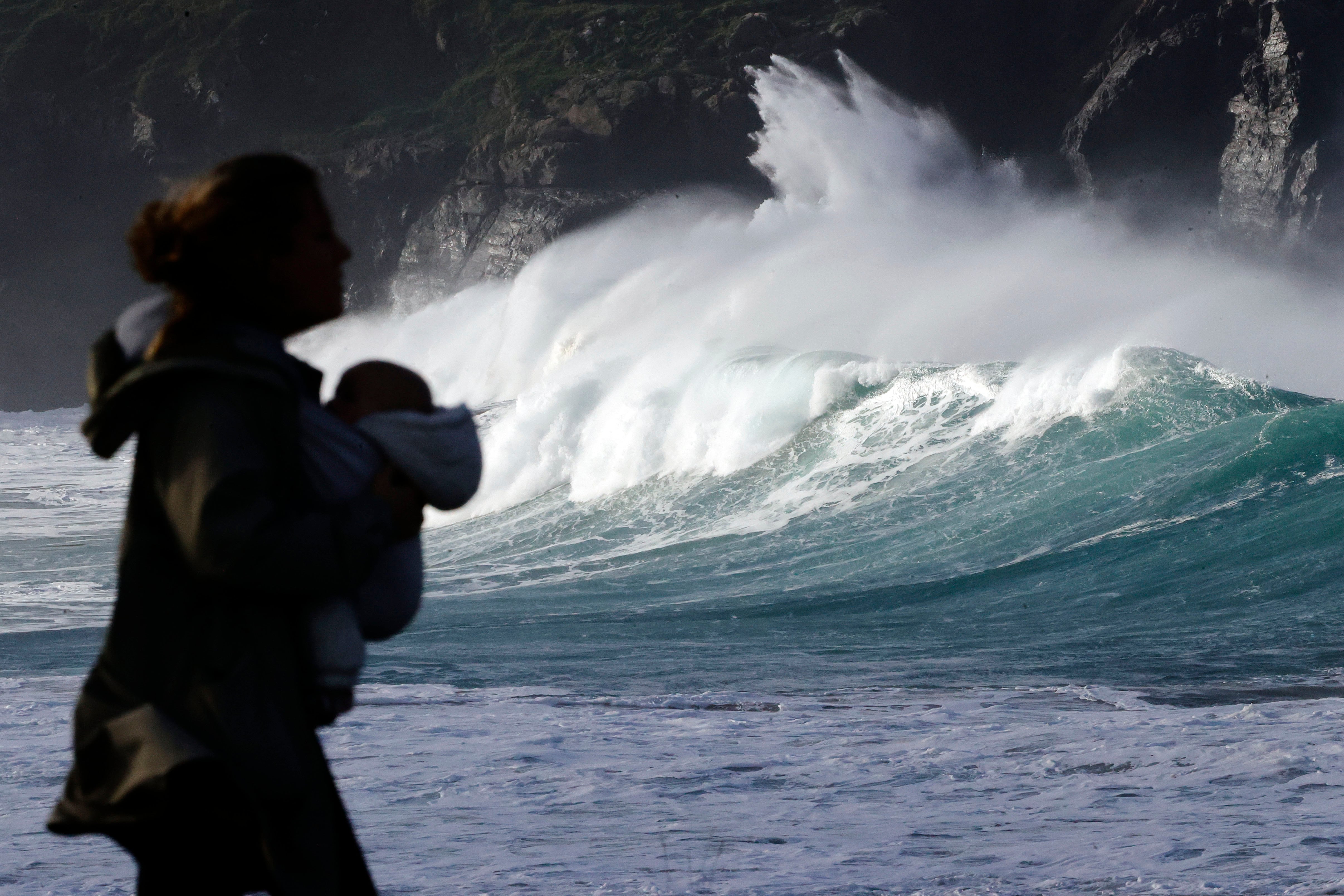 VALDOVIÑO (CORUÑA), 08/12/2025.- Una mujer pasa ante el fuerte oleaje formado este lunes en la costa de Valdoviño, en las proximidades de la Iglesia del Porto. EFE/Kiko Delgado
