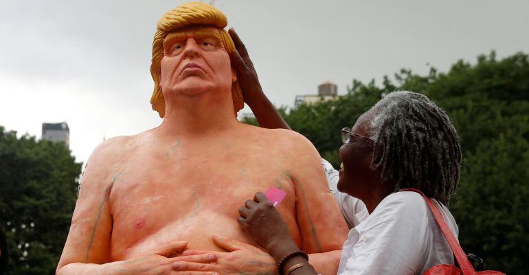 Una mujer toca la estatua que representa a Donald Trump desnudo.