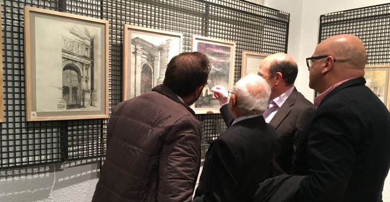 Luis Berges enseña algunos de los dibujos a varios asistentes a la inauguración de la muestra.