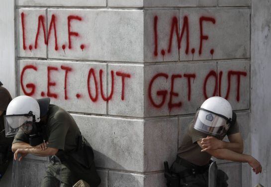 Antidisturbios descansan ante una pintada contra el FMI el 5 de mayo de 2010.