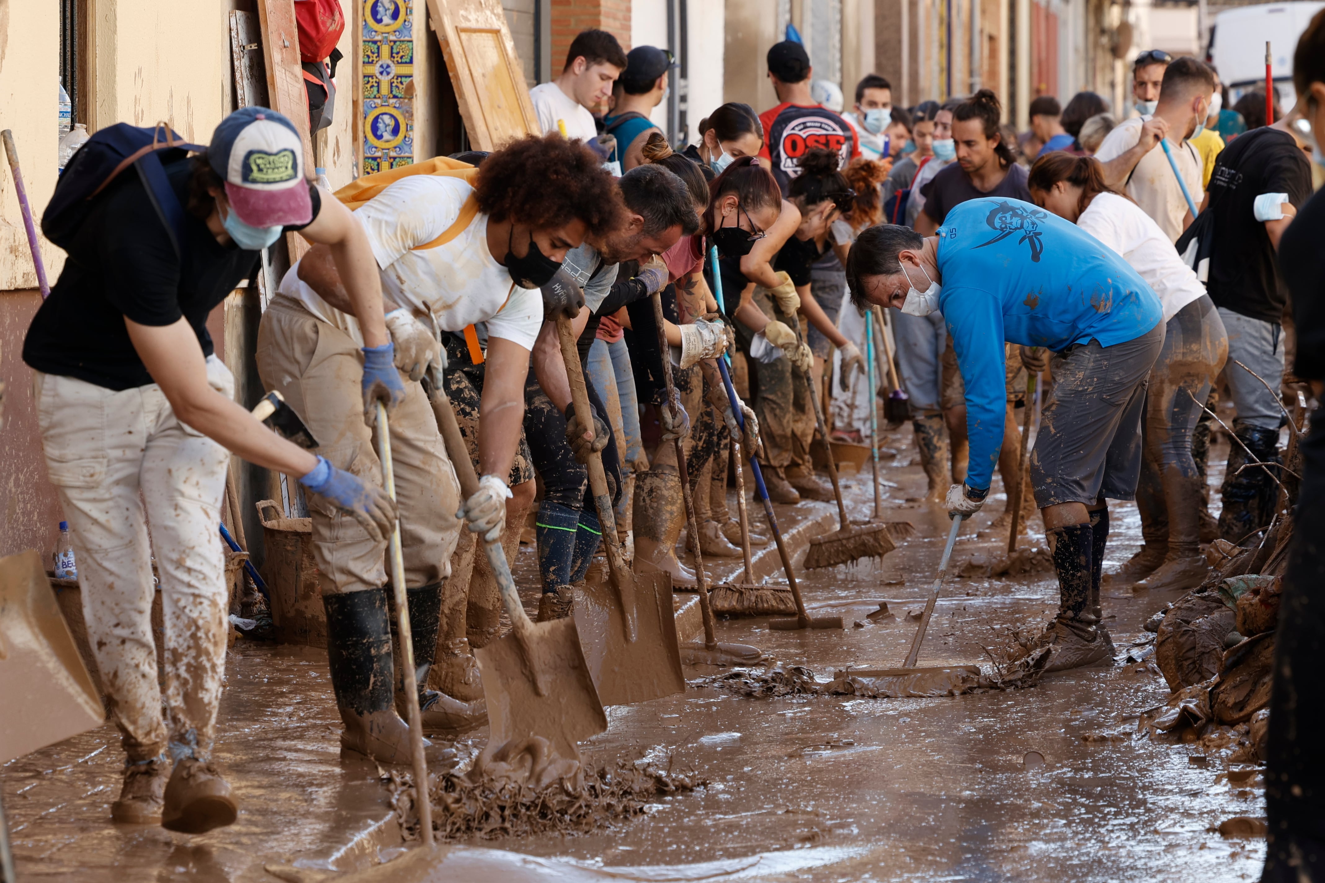 Varias personas retiran el lodo acumulado en una calle de la localidad valenciana de Paiporta, este sábado