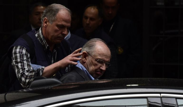 Rodrigo Rato es conducido al coche policial tras su detención.