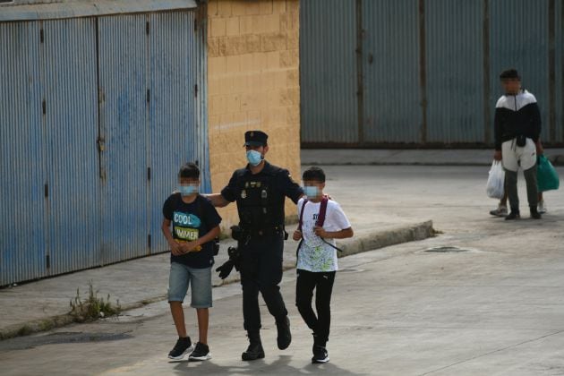 Agentes de la Policía Nacional acompañan a menores marroquíes a las naves acondicionadas