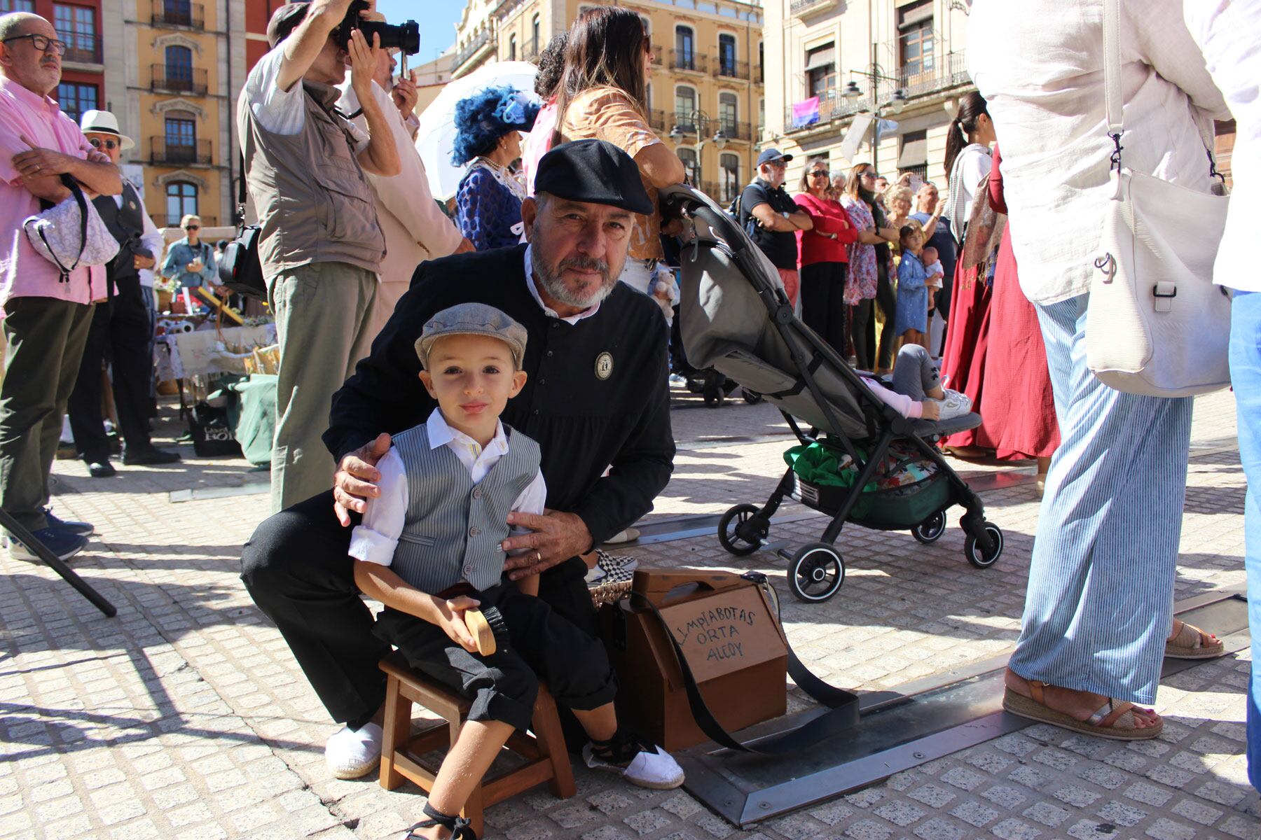 Un pequeño vestido de limpiabotas en la plaza de España acompañado por su abuelo