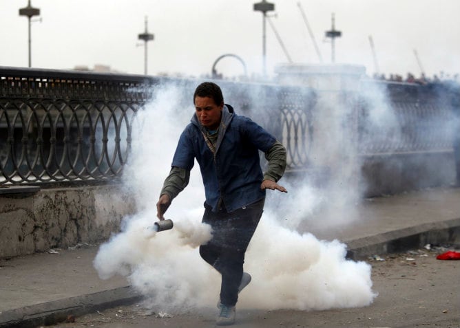 Un opositor del presidente Mohamed Mursi huye del gas lacrimógeno lanzado por la policía en el puente Qasr Al Nil, puente que conduce a la plaza Tahrir en El Cairo